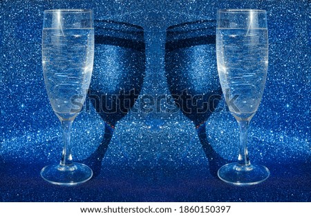 two wine glasses with sparkling champagne. blue glitter background