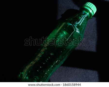 green plastic drink bottle on black background