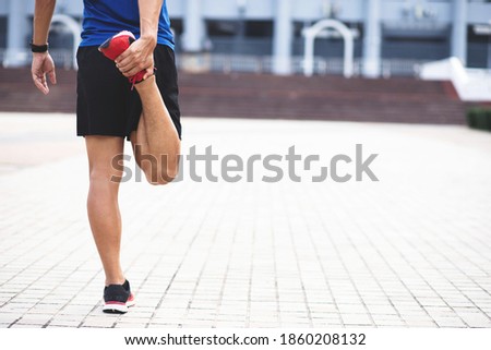 Sporty man Wearing a blue shirt .stretching exercise for warming up before running in the park or gym workout. Fitness and healthy lifestyle concept. Royalty-Free Stock Photo #1860208132