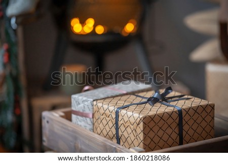 Gift boxes of beige and brown tones are in a wooden box against the background of the fire in the fireplace, blurred background, bokeh. New year and Christmas interior-blurred background. Copy space.
