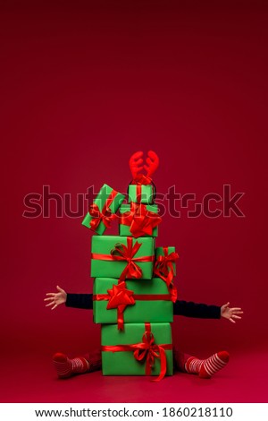 Because pyramid green Christmas gift boxes on red background in Studio, you can see arms and legs stretched out in different directions. lot gifts for Christmas. Advertising and discounts. horns deer