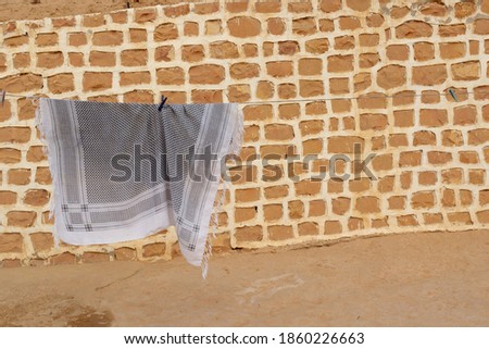 Traditional Keffiyeh or Kufiya hanging on rope against brick wall background. 