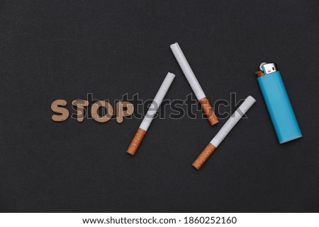 Cigarette on black background with lighter and word stop. Quit smoking