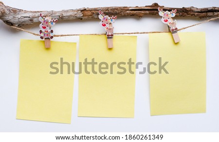 Board mood template.Eco-concept for household goods. Decorative clothespins with an image of Christmas deer on a white background, holding sheets of paper for notes.