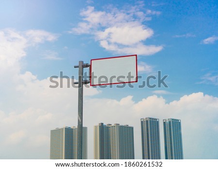 Blank road sign in the middle of city, with buildings and sky background.