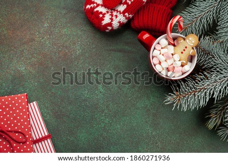 Christmas greeting card with fir tree, gift boxes and cacao cup with marshmallow, candy cane and gingerbread man. On stone background with copy space for your xmas greetings. Top view flat lay