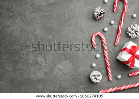 Flat lay composition with candy canes and Christmas decor on grey table. Space for text
