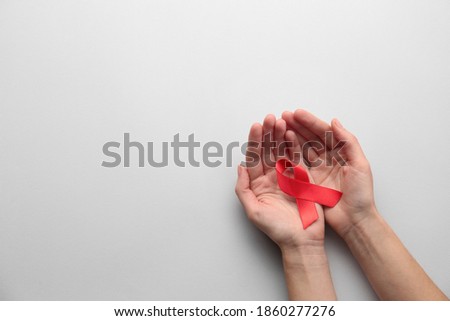 Woman holding red awareness ribbon on white background, top view with space for text. World AIDS disease day Royalty-Free Stock Photo #1860277276