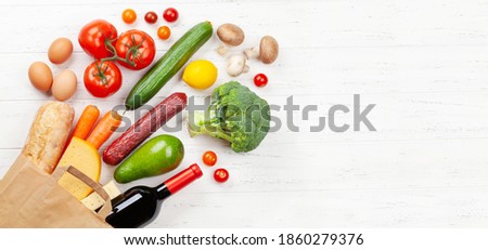 Different food in recycling paper bag on wooden table. Top view flat lay with copy space