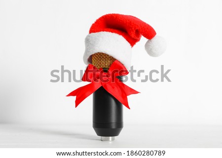 Microphone with Santa hat and red bow on white background. Christmas music