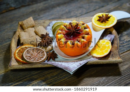 Christmas mulled wine - unusual served in orange. Hot winter drink orange,spices, anise, cinnamon on old wooden table . Selective focus.