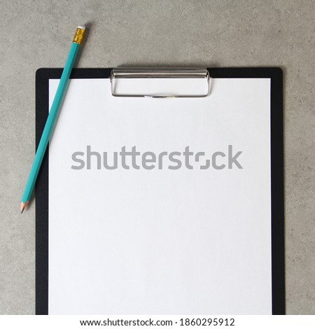 Template of white paper with simple pencil on light grey concrete background in a black tablet with a clip. Concept of new idea, business plan and strategy, development and implementation of content