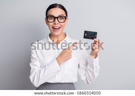 Photo of surprised girl indicate finger debit card open mouth wear specs white shirt isolated grey color background