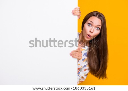 Photo portrait of amazed woman hiding behind white wall with blank space isolated on vivid yellow colored background Royalty-Free Stock Photo #1860335161