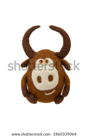 Toy bull made of felt isolate on a white background. Toy made of felted wool on a light background. Cute soft bull figurine. Symbol of 2021.