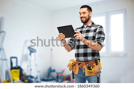 technology, construction and repair concept - happy smiling worker or builder with tablet pc computer and tools over room with building equipment background Royalty-Free Stock Photo #1860349360