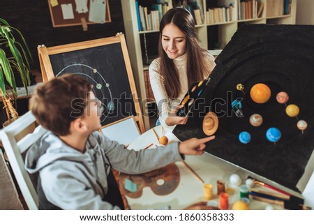 Happy school boy and girl  making a solar system for a school science project at home