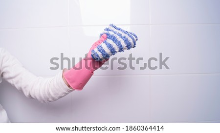 female hand in a rubber glove holding a rag for cleaning surfaces