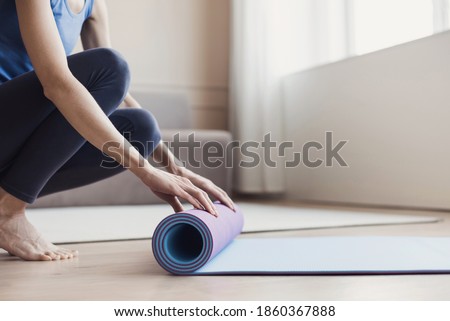 Woman rolling up exercise mat and preparing doing yoga or fitness. Home workout, yoga, balance, meditation, relaxation, healthy lifestyle, self-care, sport, training class, body care, pilates concept