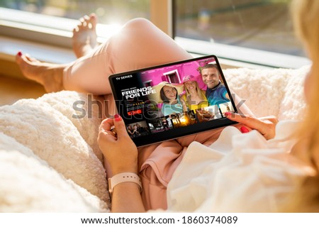 Woman relaxing at home and watching TV series on tablet Royalty-Free Stock Photo #1860374089