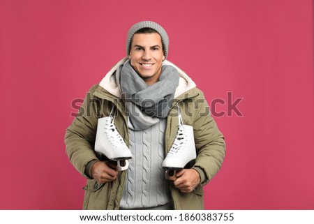Happy man with ice skates on pink background