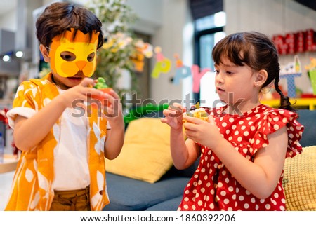 Brother and sister preparing halloween mask for upcoming festival in autumn.