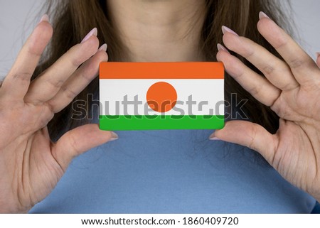 A woman shows a business card with an image of the Niger flag.