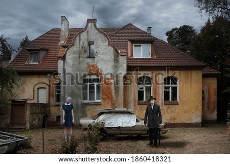 Mystical picture of an old house with corrupted frame of old car and strange persons against moody dramatic sky
