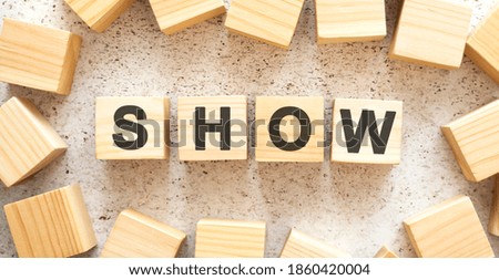The word SHOW consists of wooden cubes with letters, top view on a light background.