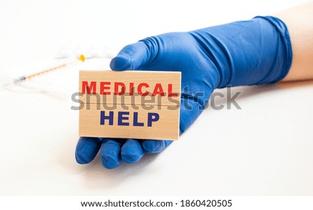 A hand in a medical glove holds wooden cubes with the inscription MEDICAL HELP.