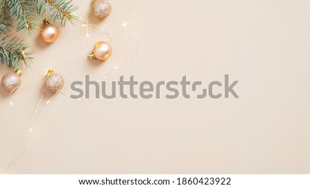 Christmas tree branches, balls and golden garland on pastel beige background. Hygge, cozy, nordic Christmas composition. Minimal style. Flat lay, top view.  