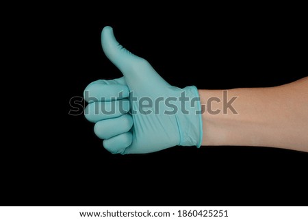 Hand in blue glove isolated on black with thumb up.

