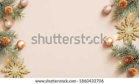 Christmas frame. Beige Xmas background with pine tree branches, golden snowflakes, balls, garland. Christmas frame, greeting card template, banner mockup. Flat lay, top view, copy space