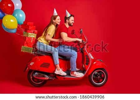 nice beautiful couple on motorcycle bringing carrying bunch air balls festive decoration isolated over red studio background, making people happy