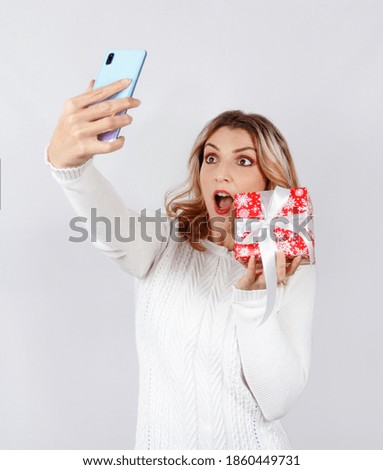 Young woman making selfie with a present on a  smartphone