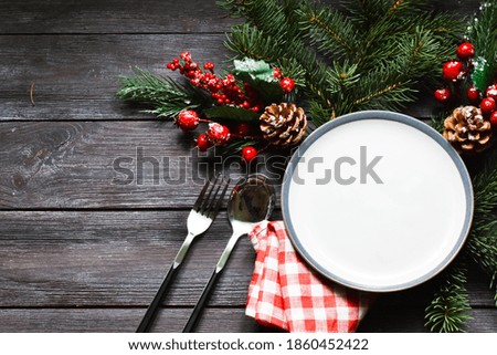 Christmas dinner plate decoration with Christmas ornaments on wood background. Merry christmas greeting card. Winter holiday theme. Happy New Year. Space for text.