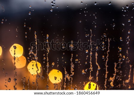 abstract background, streams of rain and snow on the glass on the background of street lighting
