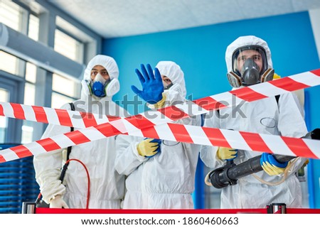 man in protective hazmat suit stops, does not let to enter building, don't allow. during coronavirus epidemic Royalty-Free Stock Photo #1860460663