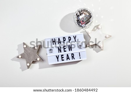 New Year or Christmas composition, flat lay, top view. Light box inscription Happy New Year, mirrored disco ball and wooden star decorations, copy space.