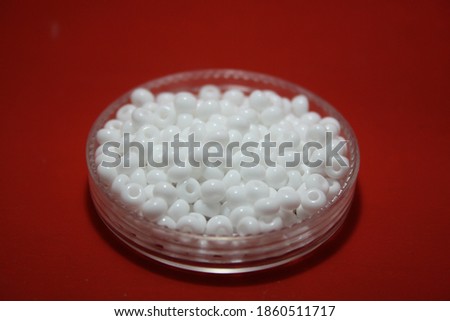 White beads in a box. Space for your text. Red background.