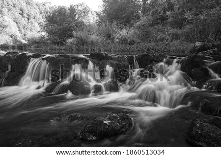 A grayscale shot of  beautiful small waterfalls in a forest - great for wallpaper or background