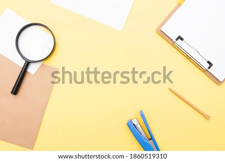 Business composition, layout with blank paper, pen, magnifier on yellow background, top view, space for text