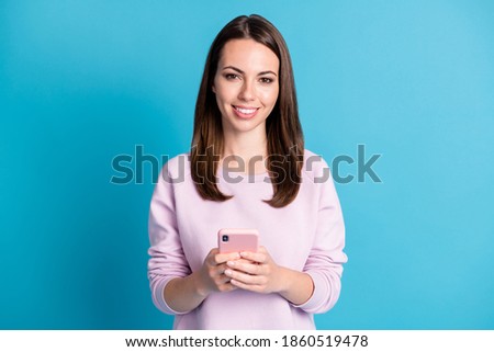 Photo of cute lovely young girl hold telephone beaming toothy smiling chat university friends invite night sleepover party wear violet pullover isolated blue color background