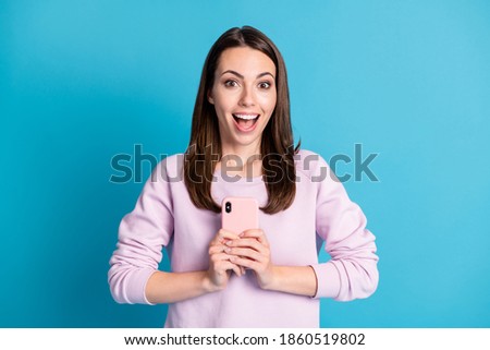 Photo of lovely cute young girl hold telephone excited look beaming smiling secretly take picture direct camera you biggest fan wear violet pullover isolated blue color background