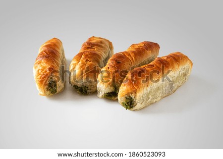 Rolled puff pastry rolls with a Golden crust, stuffed with green spinach and Suluguni cheese, on a light background
