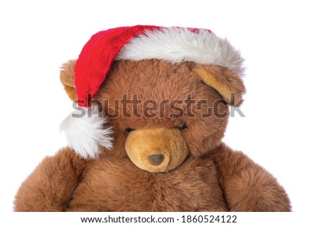 Sad teddy bear in christmas hat, isolated on white background.