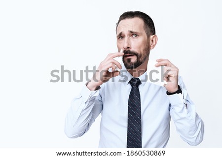 A man stands with a drug for the treatment of diseases. A man in a shirt stands and bury his nose on white. Royalty-Free Stock Photo #1860530869