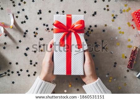 Woman hands holding Christmas gift on decorated festive table