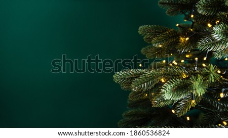 Decorated with lights Christmas tree on dark green background. Merry Christmas and Happy Holidays greeting card, frame, banner. New Year. Noel. Winter holiday theme. 