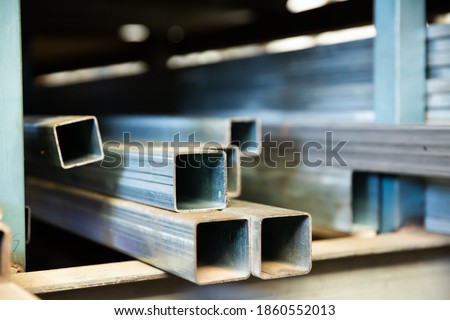 Steel structural channels, tubes and pipes of different sections and sizes on shelves. Metalworking industry concept Royalty-Free Stock Photo #1860552013